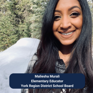 Blog contributor Maliesha Murali, a South Asian woman, smiles in a selfie taken in front of a wintry background with piles of snow and evergreens. Her hair is dark and straight, falling loosely around her face.